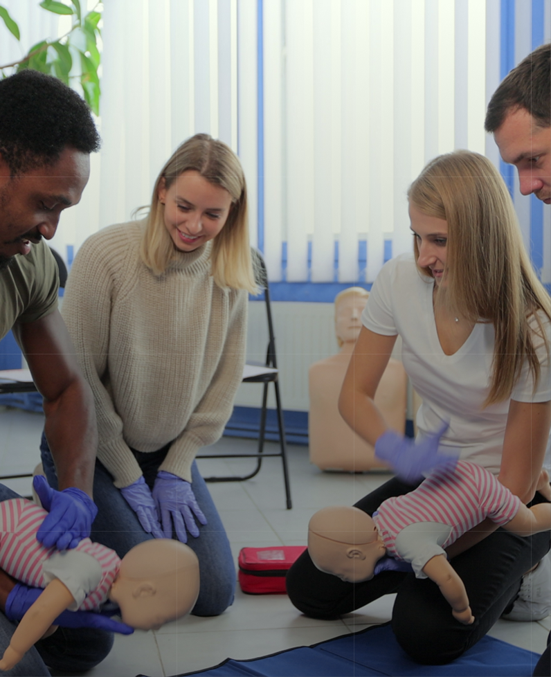 People practicing infant CPR with mannequins.