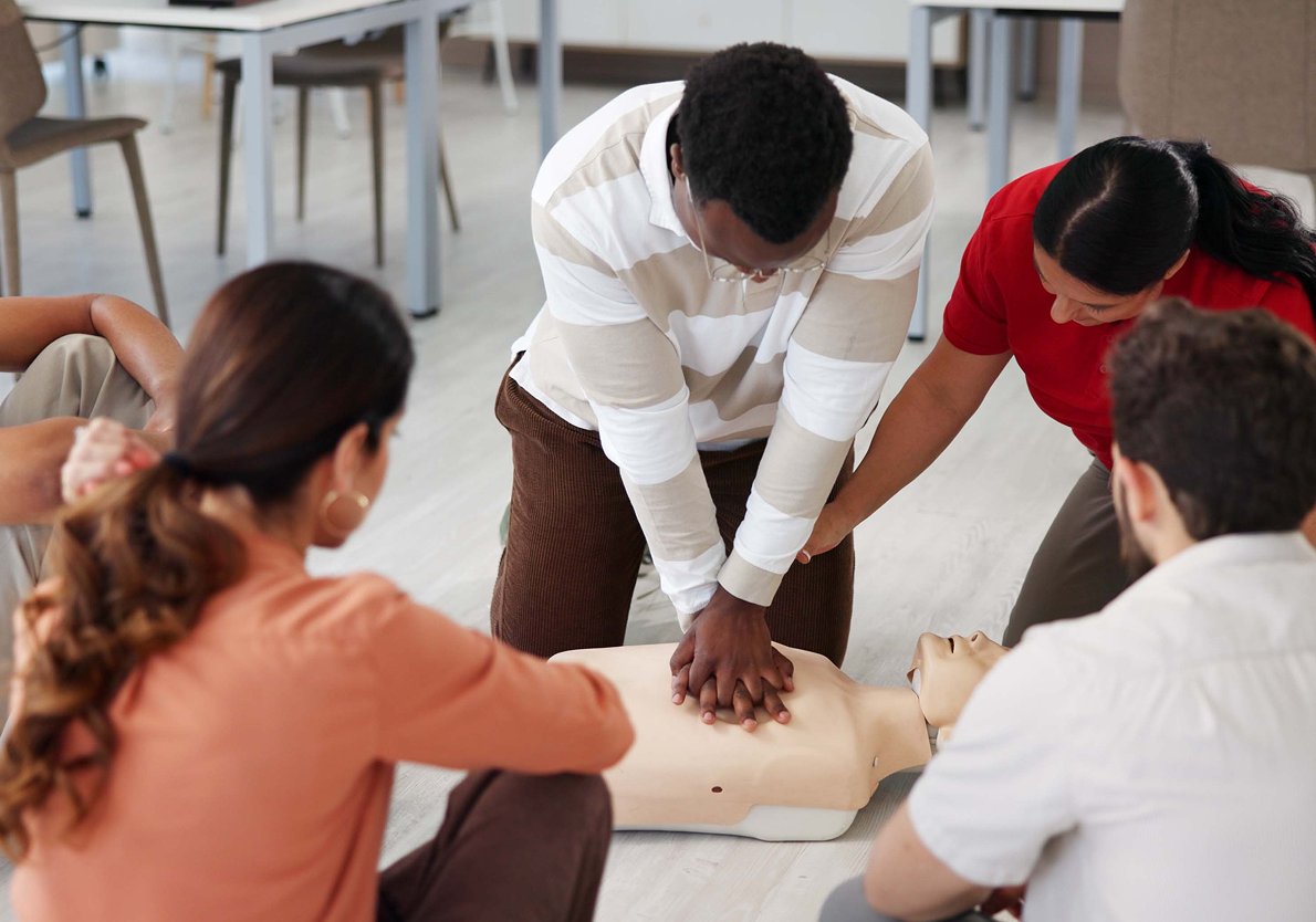 People practicing CPR on a mannequin.