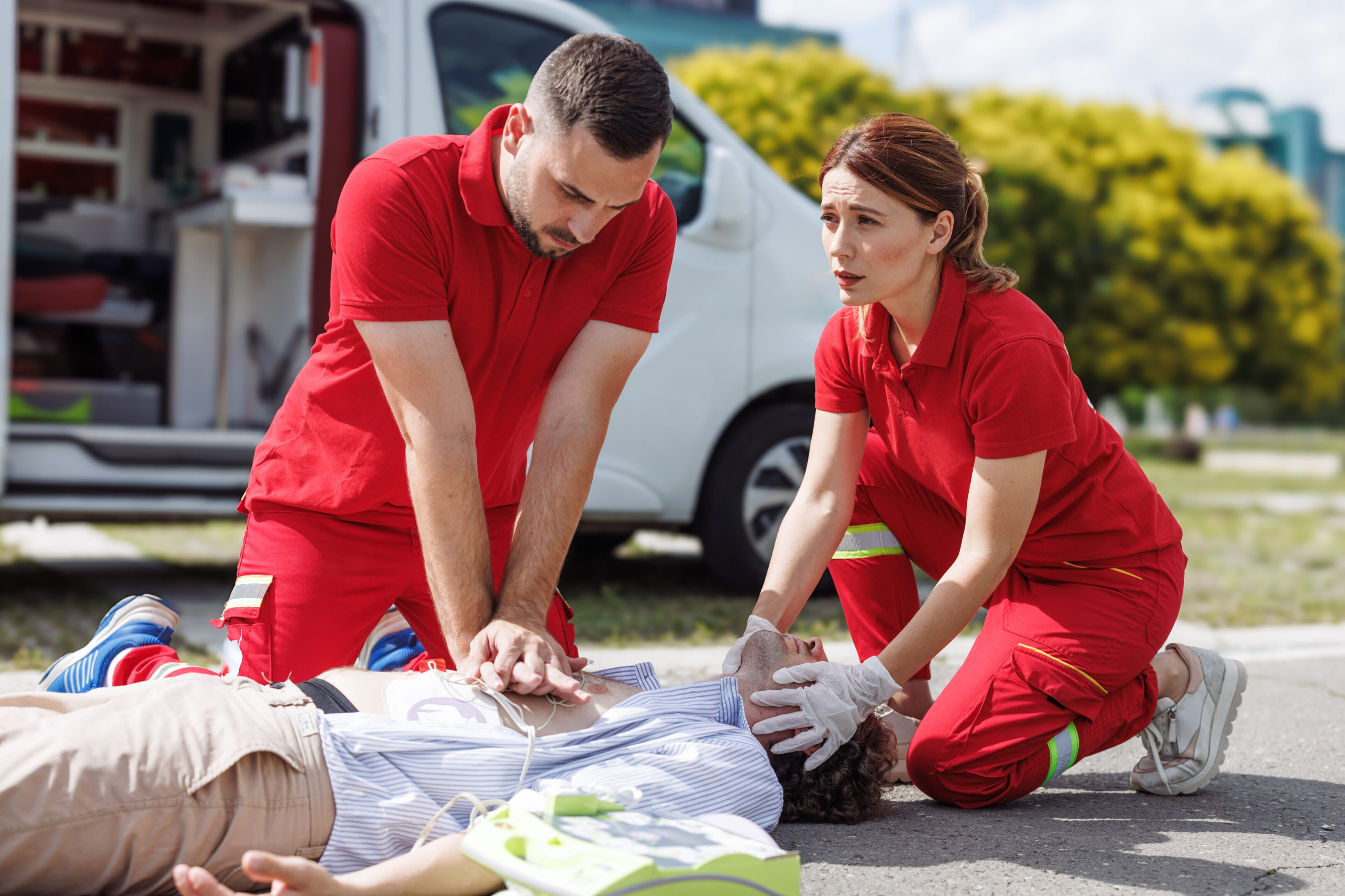 Two paramedics perform CPR on a patient on the ground. Emergency response and life-saving techniques administered.