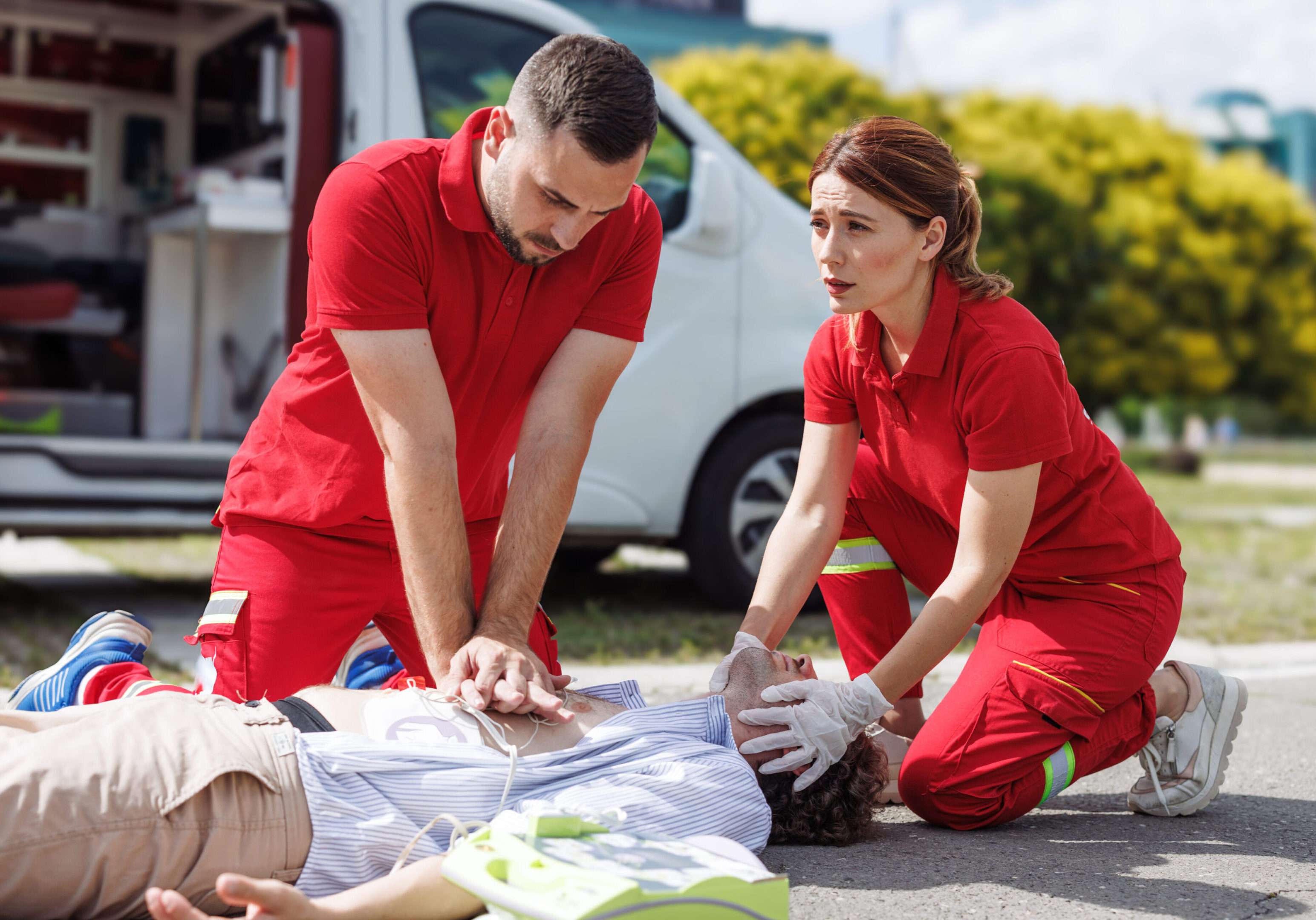 Two paramedics perform CPR on a patient on the ground. Emergency response and life-saving techniques administered.